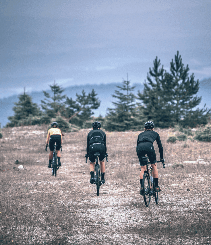 Three cyclists riding gravel bikes on a dirt trail